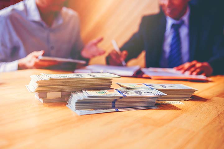Businessman puts signature on contract at business meeting and passing money after negotiations with business partners. Selected focus at money