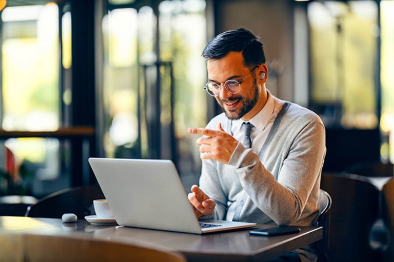Why the Smartest Investors Borrow Against Their Stocks Instead of Selling;A happy trendy manager is sitting in cafeteria and having online meeting on a laptop.